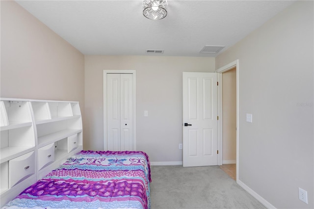 bedroom featuring light colored carpet, a textured ceiling, and a closet