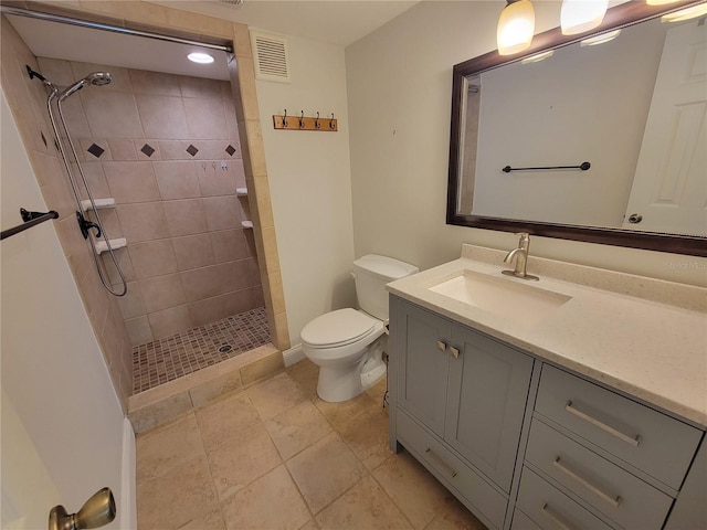 bathroom with tiled shower, vanity, and toilet