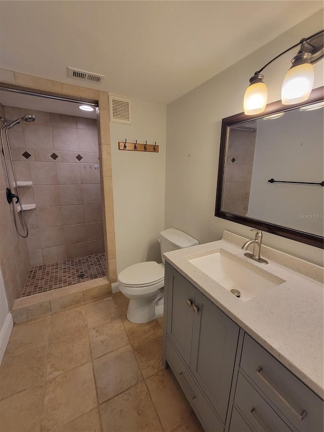 bathroom with a tile shower, vanity, and toilet