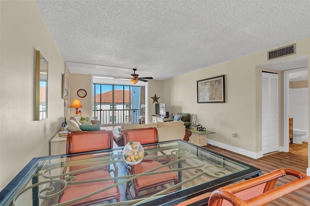 dining room featuring hardwood / wood-style flooring, ceiling fan, and a textured ceiling