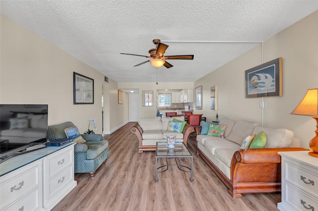 living room featuring a textured ceiling, ceiling fan, and light hardwood / wood-style flooring