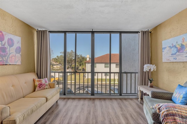 living room featuring hardwood / wood-style floors, a wall of windows, and a textured ceiling