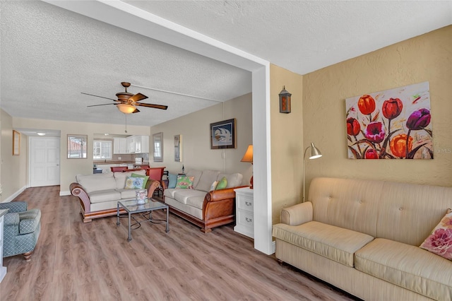 living room with ceiling fan, light hardwood / wood-style flooring, and a textured ceiling