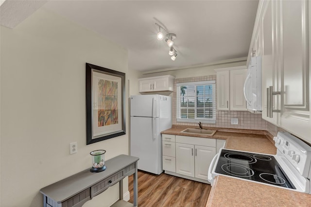 kitchen featuring tasteful backsplash, white cabinetry, sink, light wood-type flooring, and white appliances