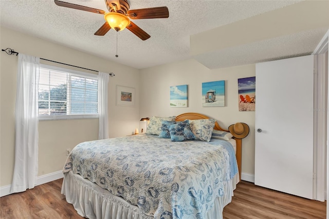 bedroom featuring ceiling fan, wood-type flooring, and a textured ceiling