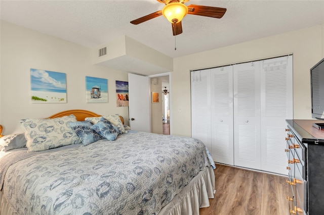 bedroom with ceiling fan, wood-type flooring, a closet, and a textured ceiling