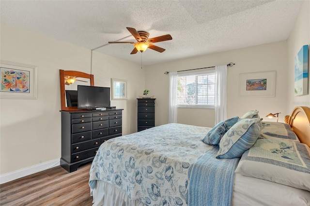 bedroom featuring ceiling fan, wood-type flooring, and a textured ceiling