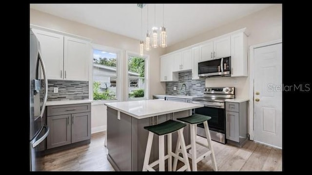 kitchen with white cabinetry, a kitchen island, stainless steel appliances, and gray cabinetry