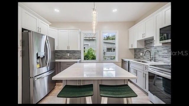 kitchen with white cabinetry, a kitchen breakfast bar, and appliances with stainless steel finishes