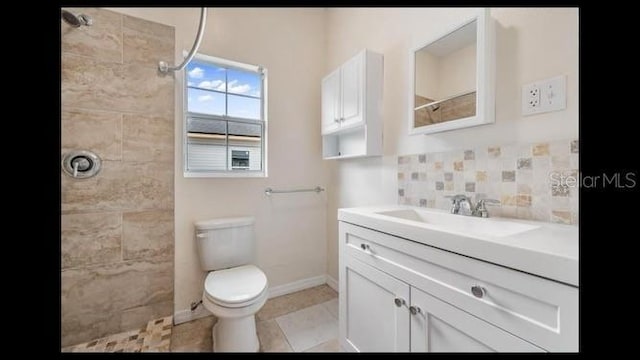 bathroom featuring decorative backsplash, vanity, tiled shower, toilet, and tile patterned floors