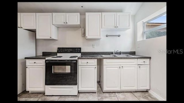 kitchen with electric range oven, stainless steel fridge, sink, and white cabinets