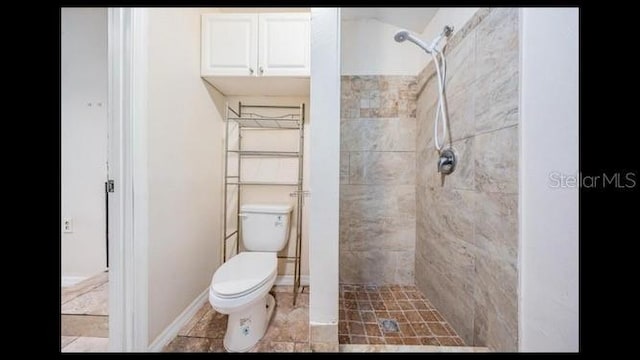 bathroom featuring tiled shower and toilet