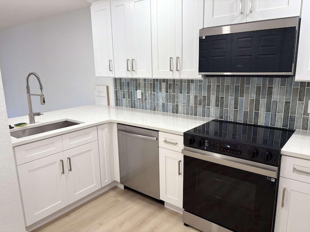 kitchen with white cabinetry, sink, stainless steel dishwasher, kitchen peninsula, and black electric range