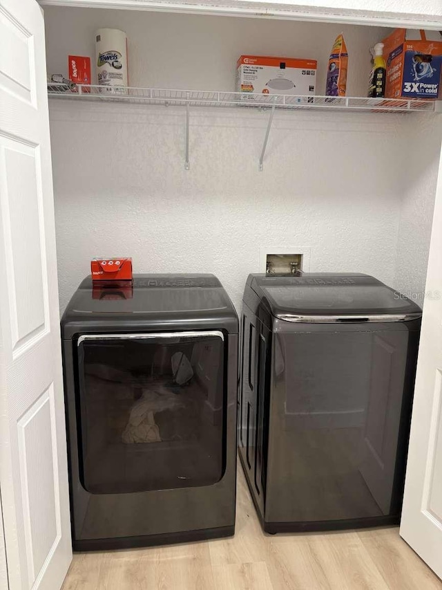 clothes washing area with separate washer and dryer and light hardwood / wood-style floors