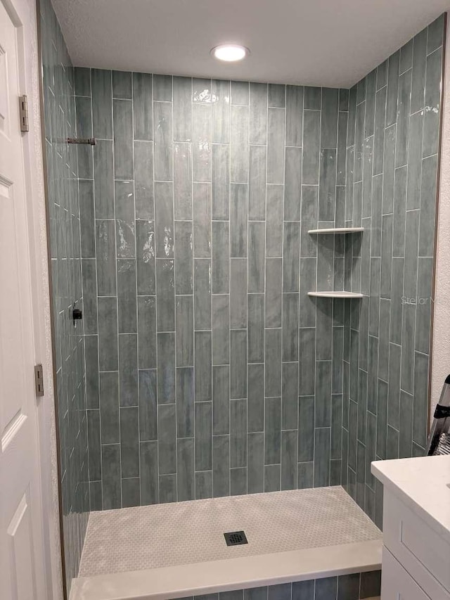 bathroom with vanity and tiled shower