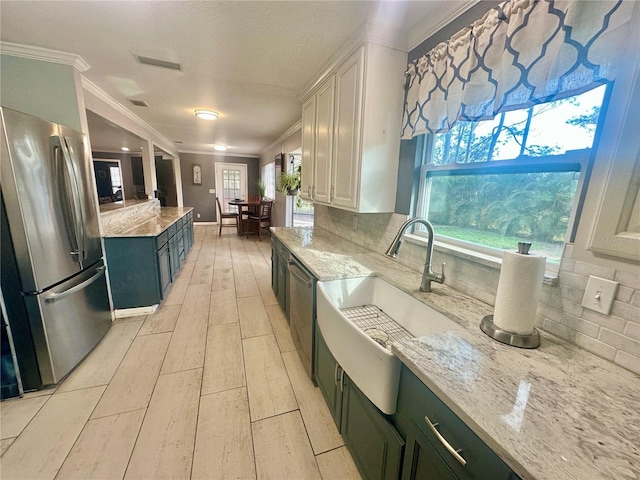 kitchen with light stone counters, crown molding, white cabinets, stainless steel appliances, and backsplash