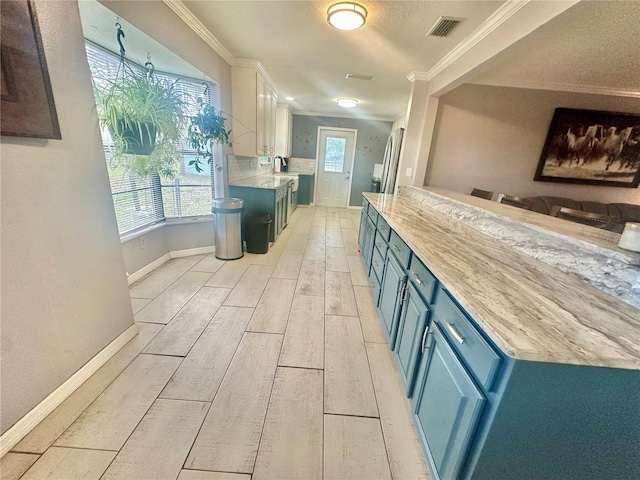 kitchen with white cabinetry, ornamental molding, blue cabinets, and backsplash