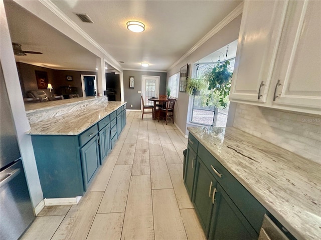 kitchen with decorative backsplash, ornamental molding, light stone countertops, and white cabinets