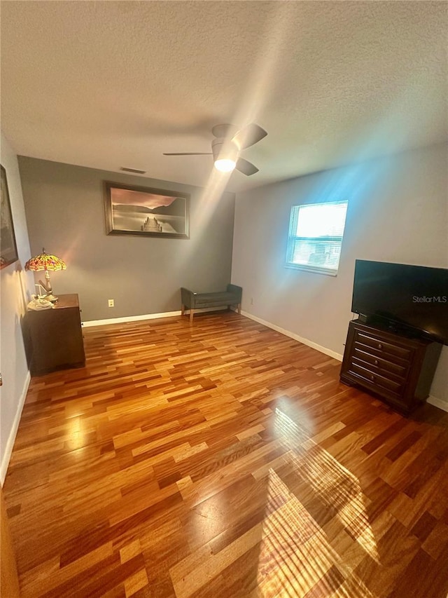 additional living space with ceiling fan, wood-type flooring, and a textured ceiling