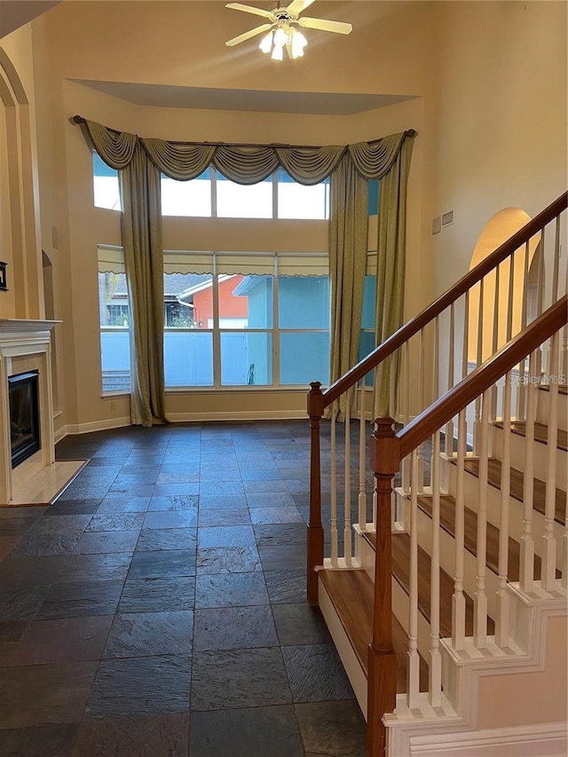 interior space featuring ceiling fan, a high end fireplace, and a high ceiling