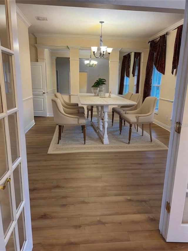 dining space featuring crown molding, wood-type flooring, and a chandelier