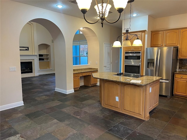 kitchen with built in shelves, stone countertops, decorative light fixtures, a kitchen island, and stainless steel appliances