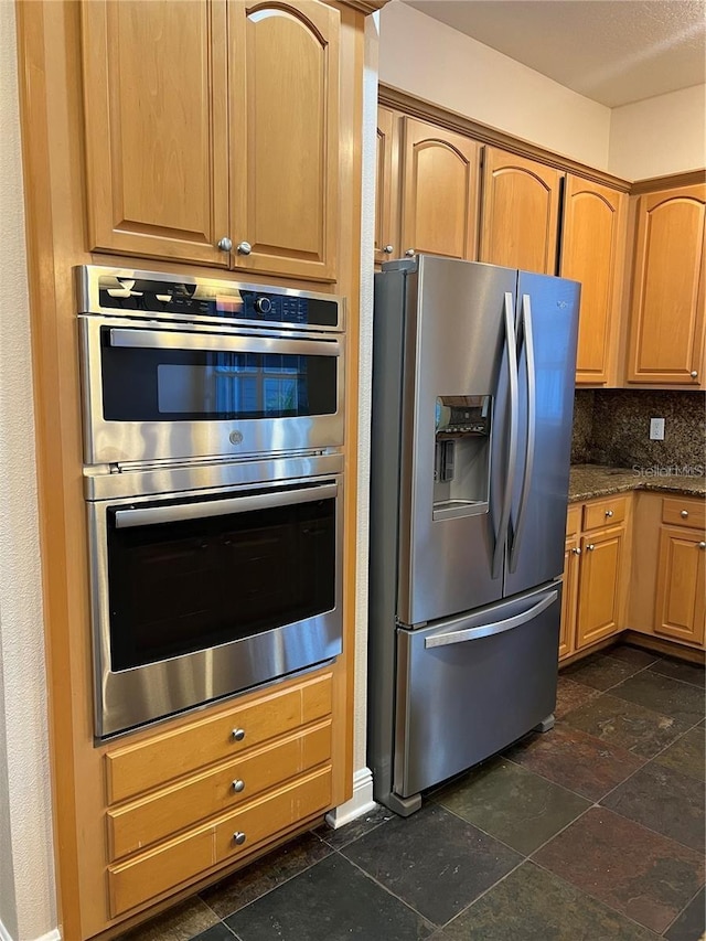 kitchen with decorative backsplash, stainless steel appliances, and dark stone counters