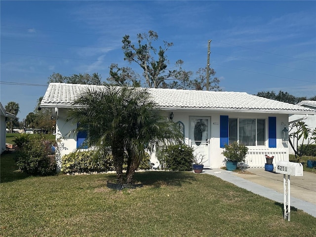 view of front of house featuring covered porch, a front yard, a tile roof, and stucco siding