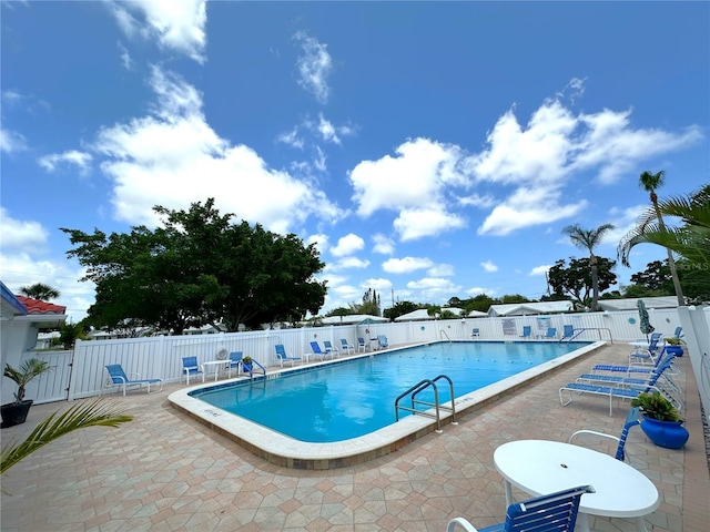 pool with a patio area and fence