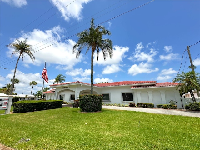 mediterranean / spanish-style house featuring a tiled roof, a front lawn, and stucco siding