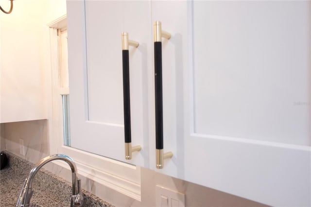 details featuring stone counters, a sink, and white cabinetry