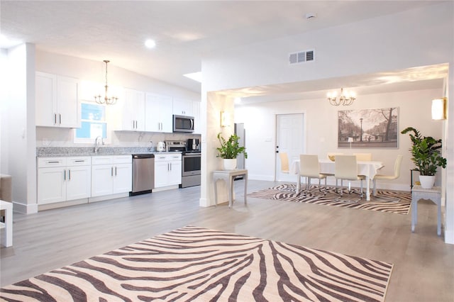 kitchen with white cabinets, stainless steel appliances, and a notable chandelier