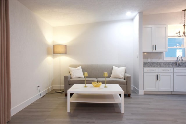 living room featuring a textured ceiling, light wood finished floors, and baseboards