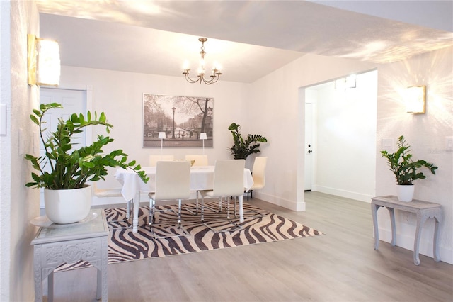 dining room featuring a chandelier, baseboards, and light wood finished floors