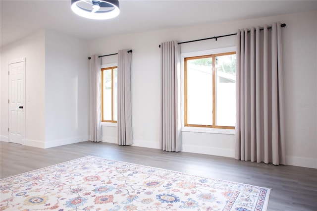 spare room featuring plenty of natural light, baseboards, radiator heating unit, and wood finished floors