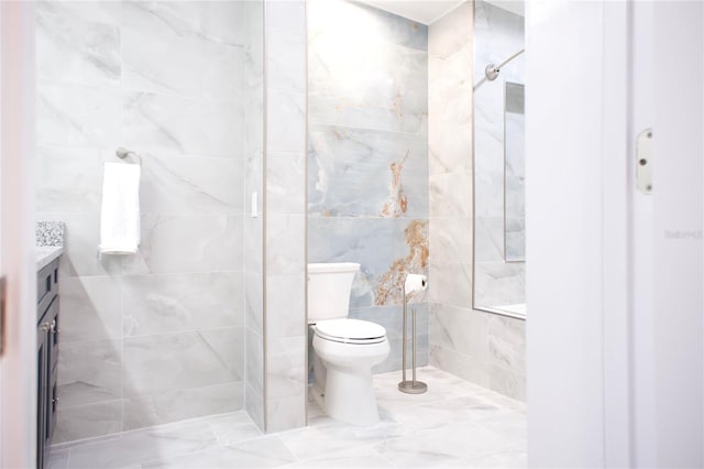 full bathroom featuring toilet, a tile shower, tile walls, and vanity