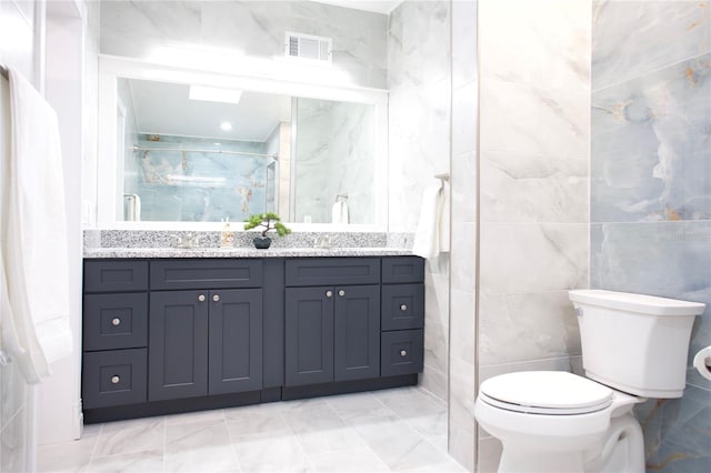 full bath with double vanity, visible vents, toilet, a shower stall, and a sink