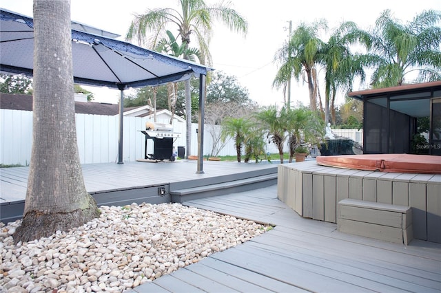 deck with area for grilling, fence, a sunroom, a gazebo, and a hot tub