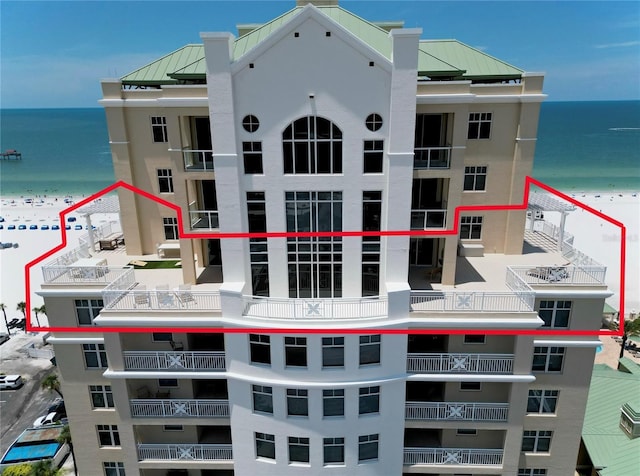 view of building exterior with a water view and a view of the beach