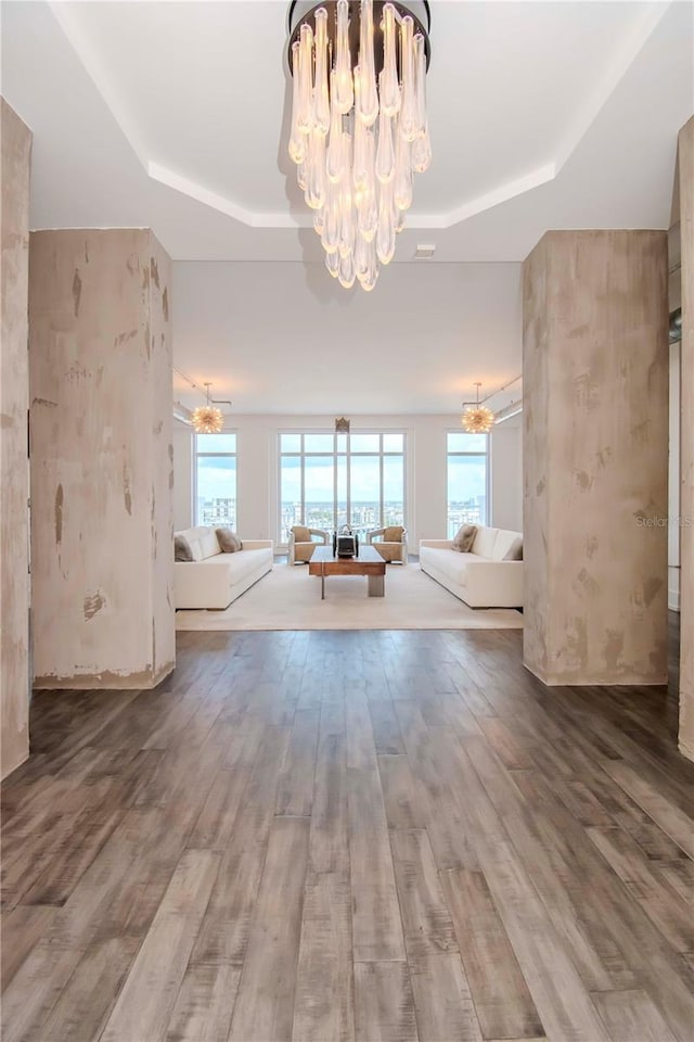 interior space with hardwood / wood-style flooring, a raised ceiling, and a chandelier