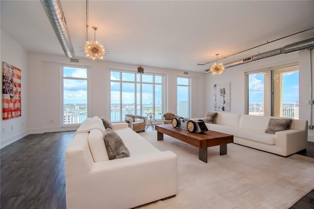 living room featuring hardwood / wood-style flooring, a water view, and a notable chandelier