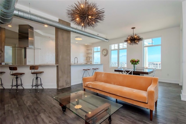 living room featuring sink, an inviting chandelier, and dark hardwood / wood-style flooring