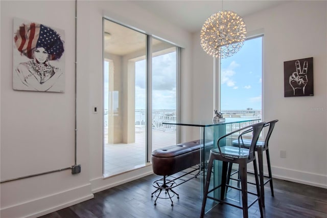 dining area with a water view, an inviting chandelier, and dark hardwood / wood-style flooring