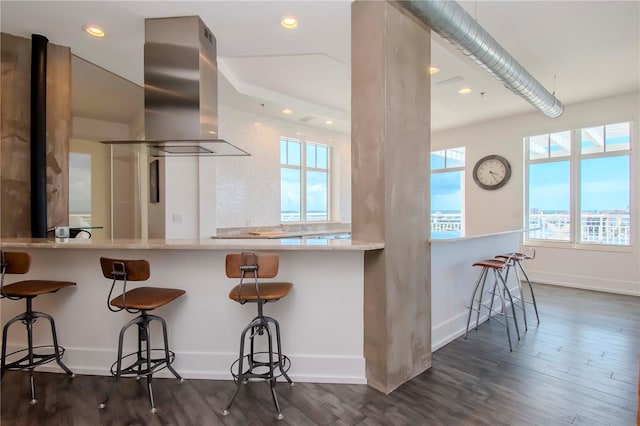 kitchen with dark hardwood / wood-style flooring, island range hood, a kitchen bar, and kitchen peninsula