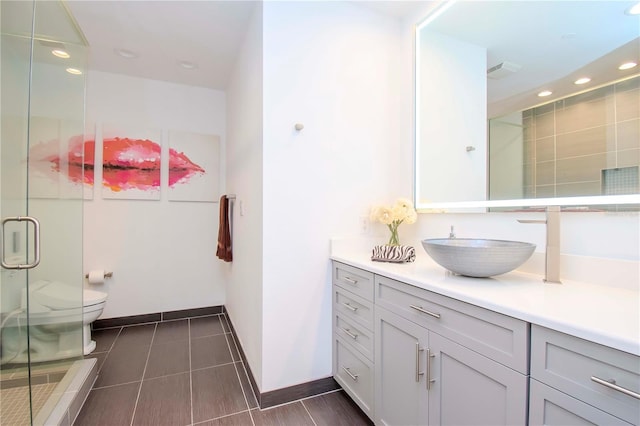 bathroom with tile patterned floors, vanity, toilet, and a shower with shower door