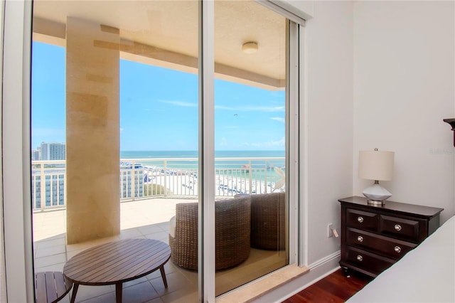 bedroom featuring a water view, hardwood / wood-style floors, and a view of the beach