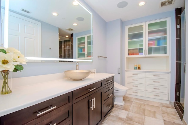 bathroom with a shower with door, vanity, and toilet