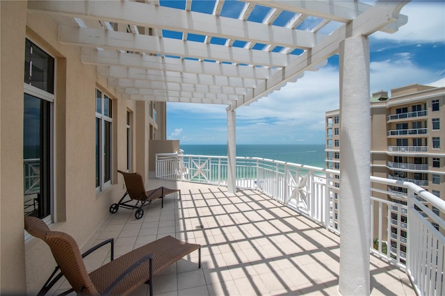 balcony featuring a water view, a view of the beach, and a pergola