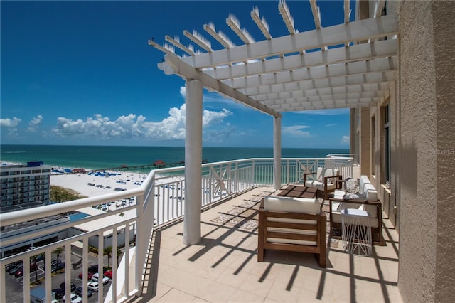 view of patio featuring a pergola, a beach view, a balcony, and a water view