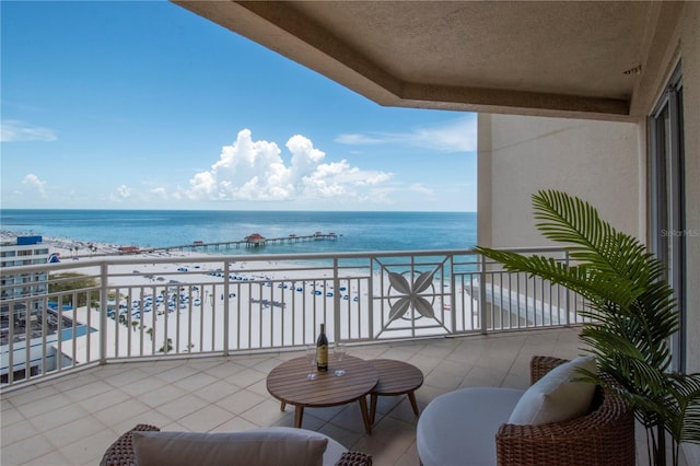 balcony featuring a view of the beach and a water view